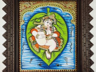 A handcrafted Alilai Krishna Tanjore painting with 22K gold foil and Jaipur gemstones, framed in premium teakwood. Perfect for pooja rooms, housewarming gifts, and spiritual décor. Ready to ship globally