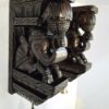 The Wooden Elephant Wall Bracket Pair in brown finish features two intricately carved elephant heads adorned with brass bells, perfect for wall décor at door entrances.