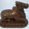The Wooden Nandi Statue, a 14-inch hand-carved masterpiece, embodies the essence of Shivas sacred bull seated on a rectangular base, making it an ideal piece for home and Hindu religious decor.