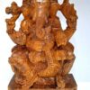 The Wooden Ganesha Statue, a 18-inch large sculpture named Ganapathi Vinayaka Vigneshwara, features Ganesha cross-legged with four arms holding items like a conch shell and axe. Adorned on a decorative pedestal, this temple figurine captures attention with its intricate details.