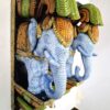 A pair of wooden elephant wall corbels in a multicolor finish featuring two blue elephant heads with green, orange, and gold accents, adorned with brass bells at the bottom.